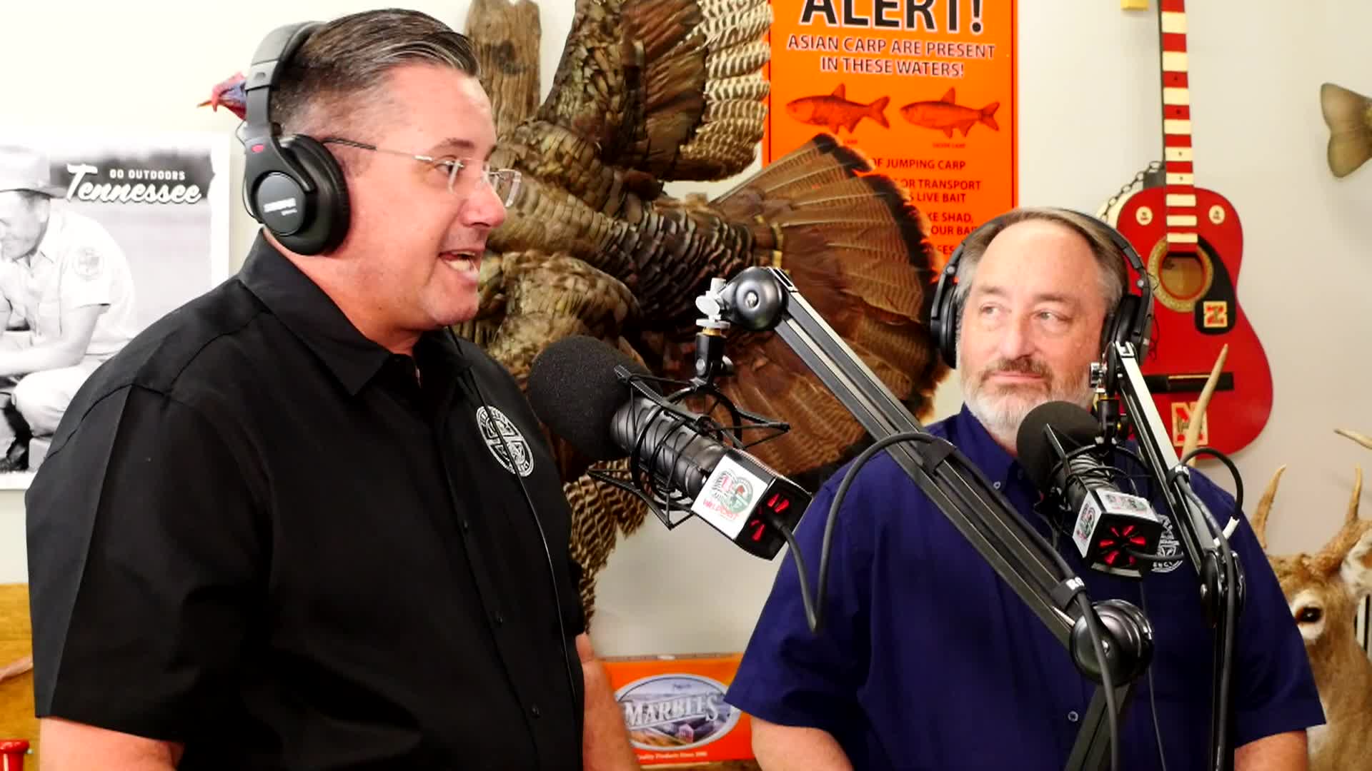 Two people speaking into microphones on a podcast about wildlife 