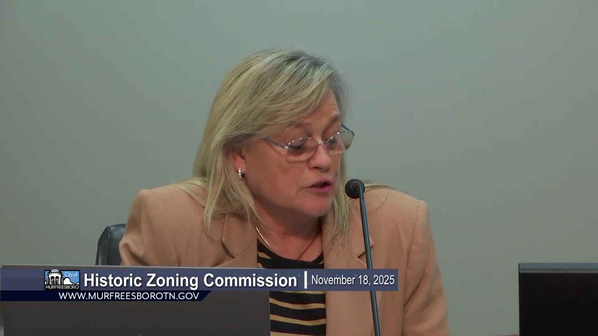 woman in tan suit speaking on agenda items in Historic Zoning Commission meeting