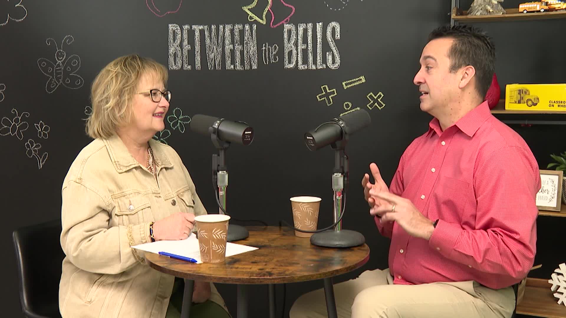 woman and man at table talking into microphones